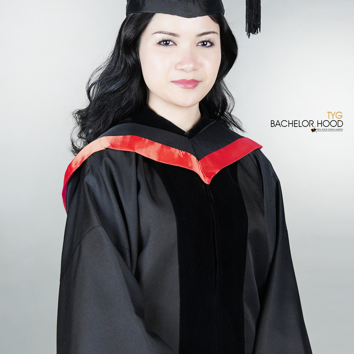 Graduate in black graduation gown with a red bachelor hood against a plain background
