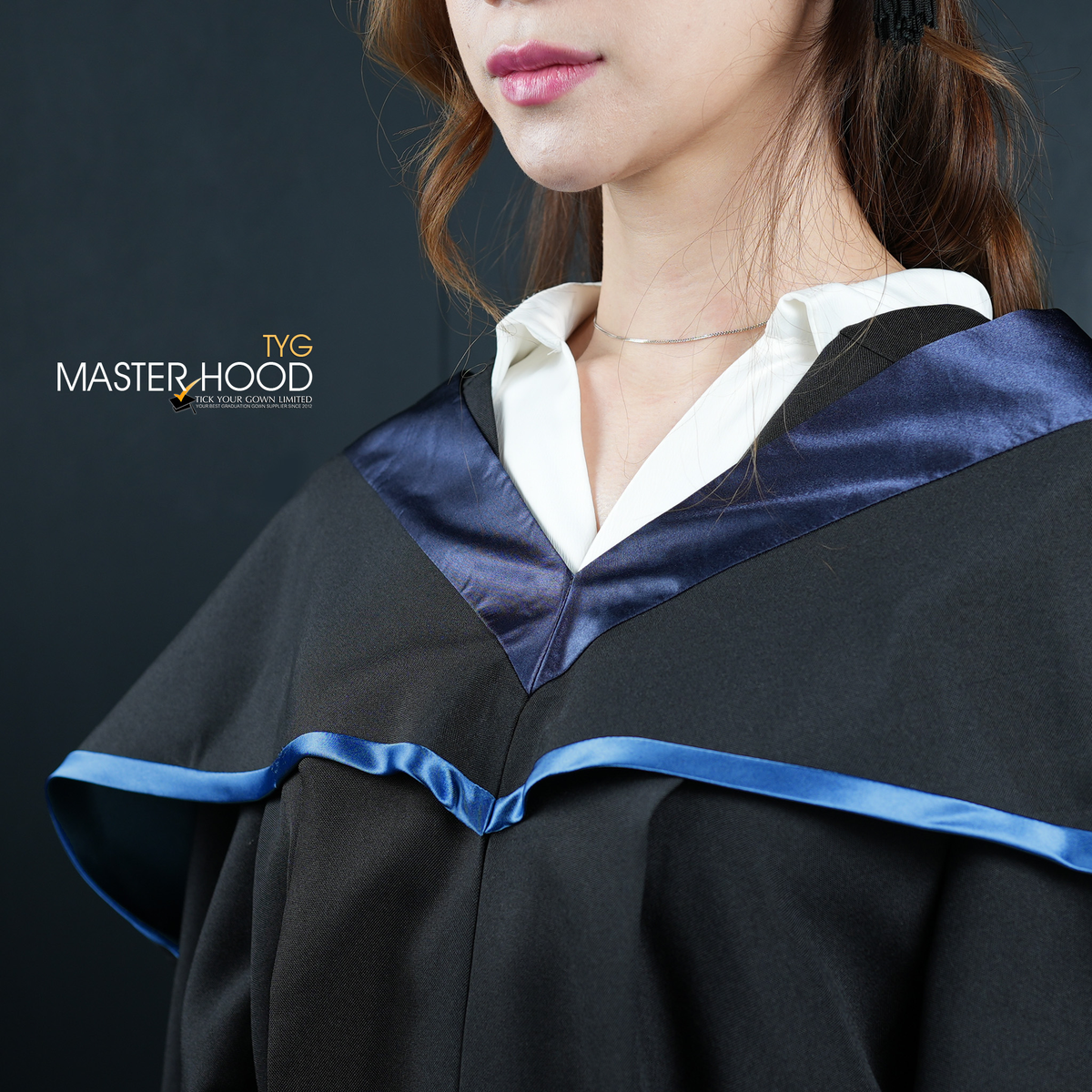 Profile view of a person wearing a black graduation gown and hood with a sky blue trim on a dark background