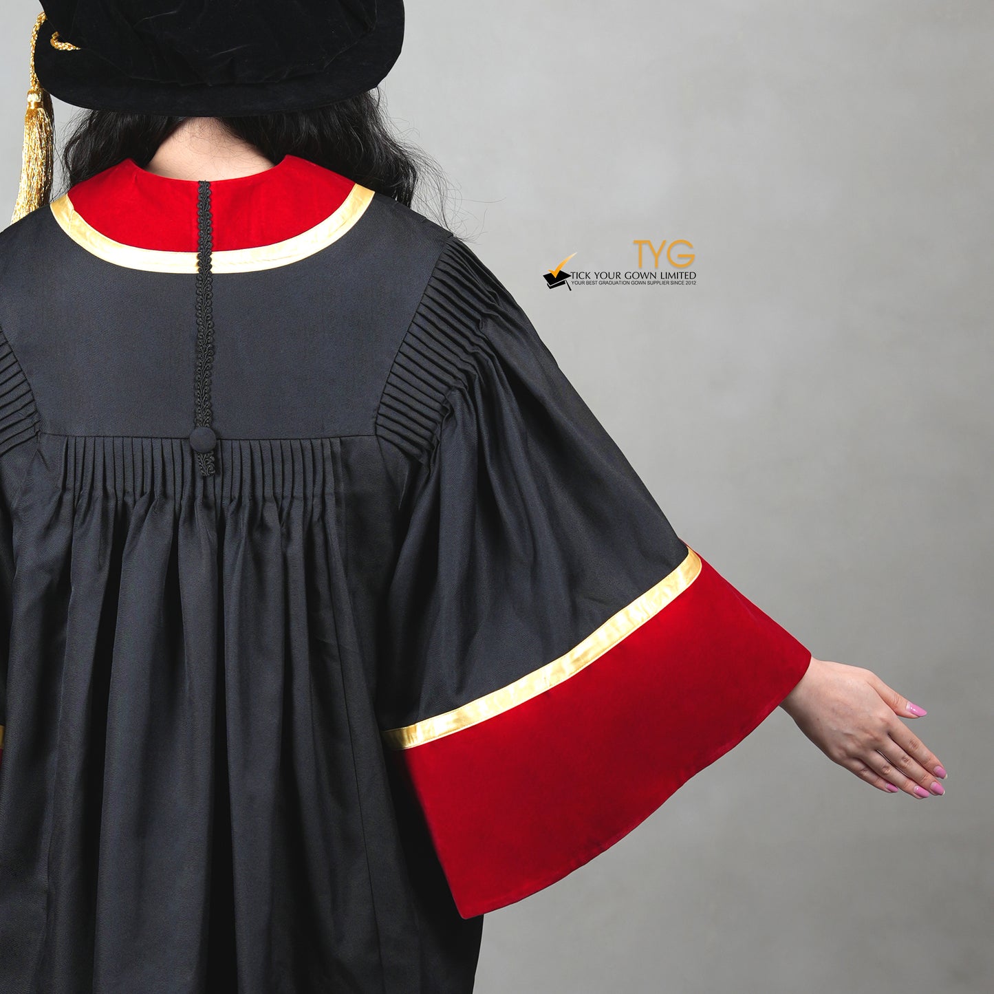 A detailed back view of a person wearing a black graduation gown with red and gold accents on a gray background