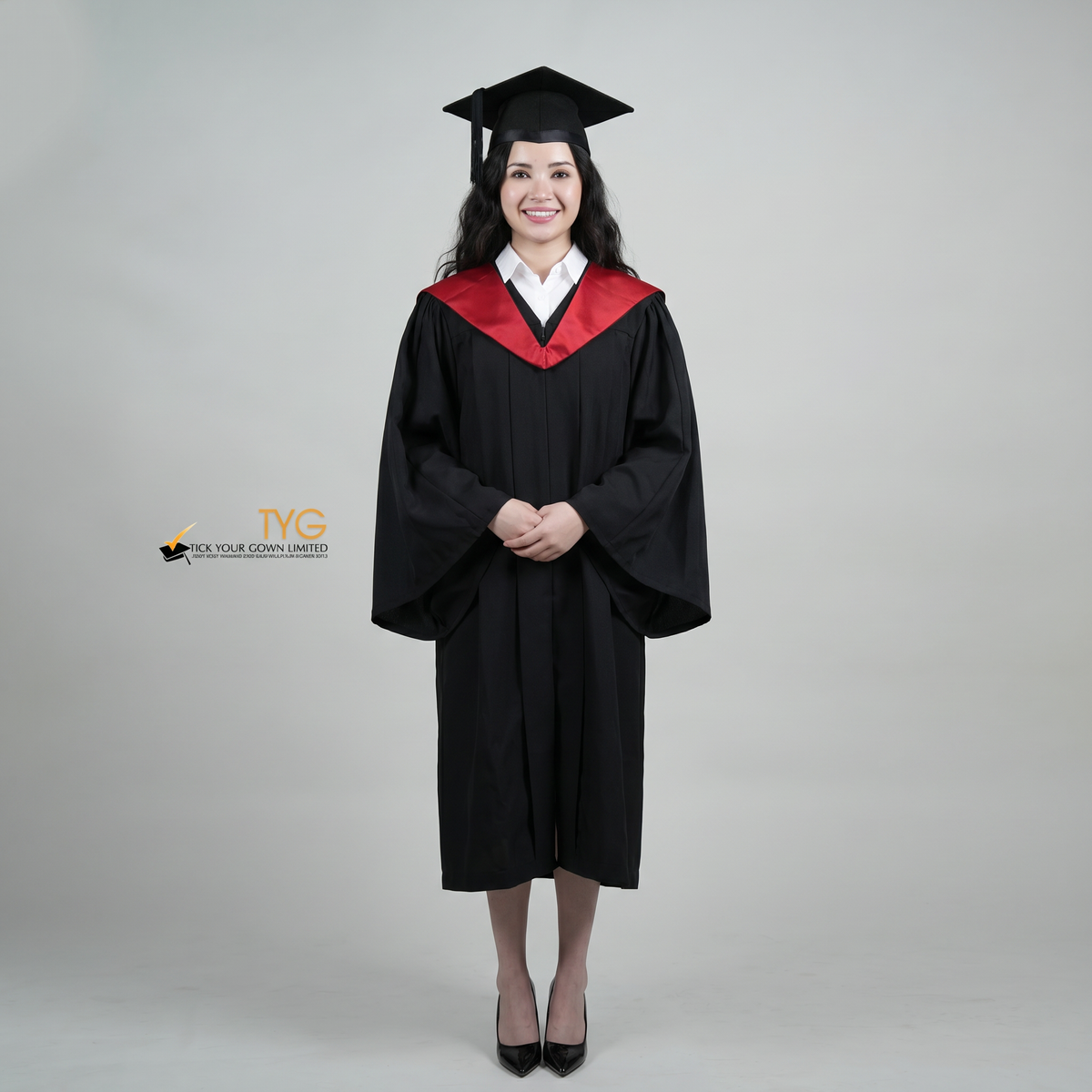A woman wearing a University of Edinburgh bachelor graduation gown and a black mortarboard cap stands against a light gray studio background. 

The gown has a red and black draped hood, and she is wearing a white collared shirt underneath.