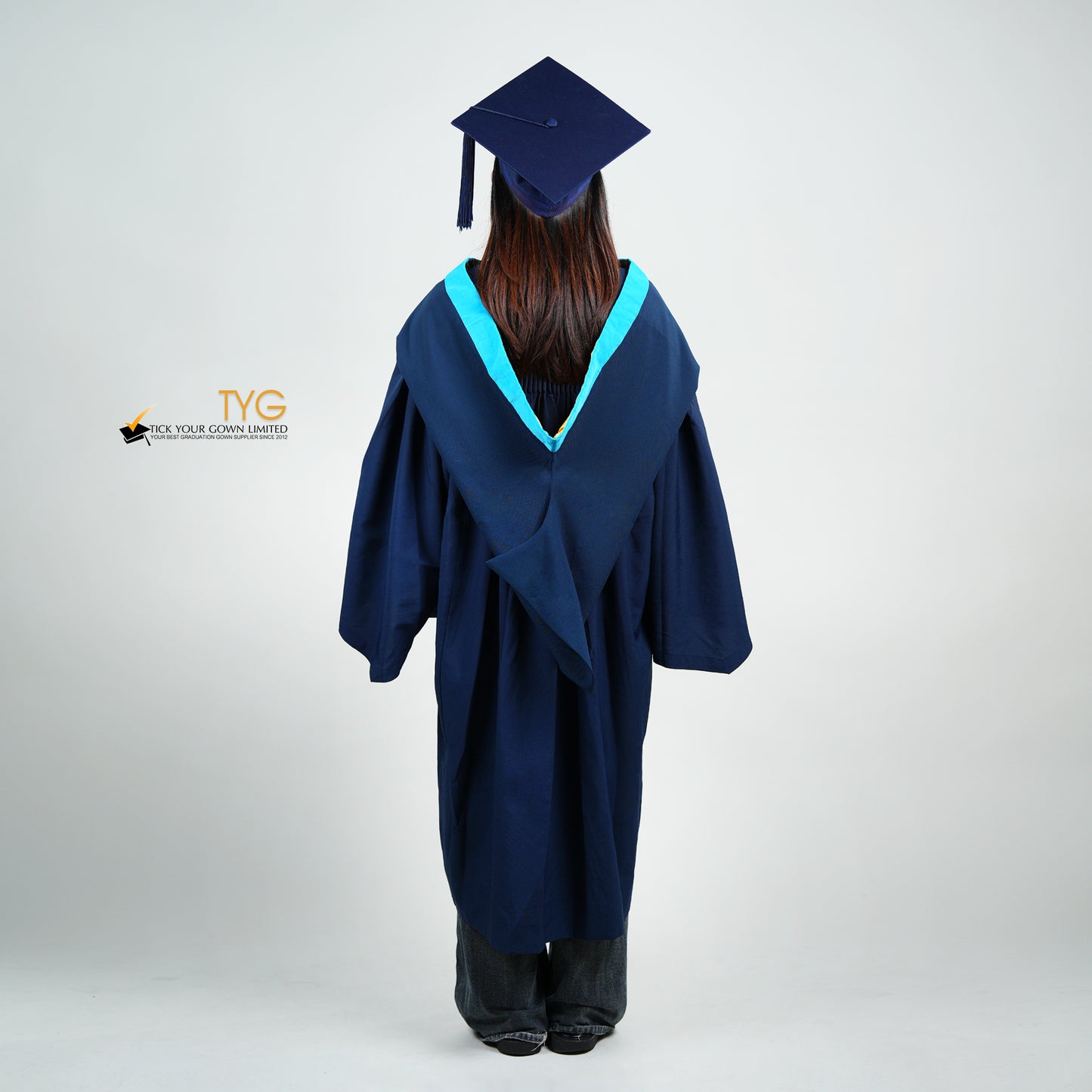 A back view of a person wearing a navy blue graduation gown and cap on a white background with TYG logo.
