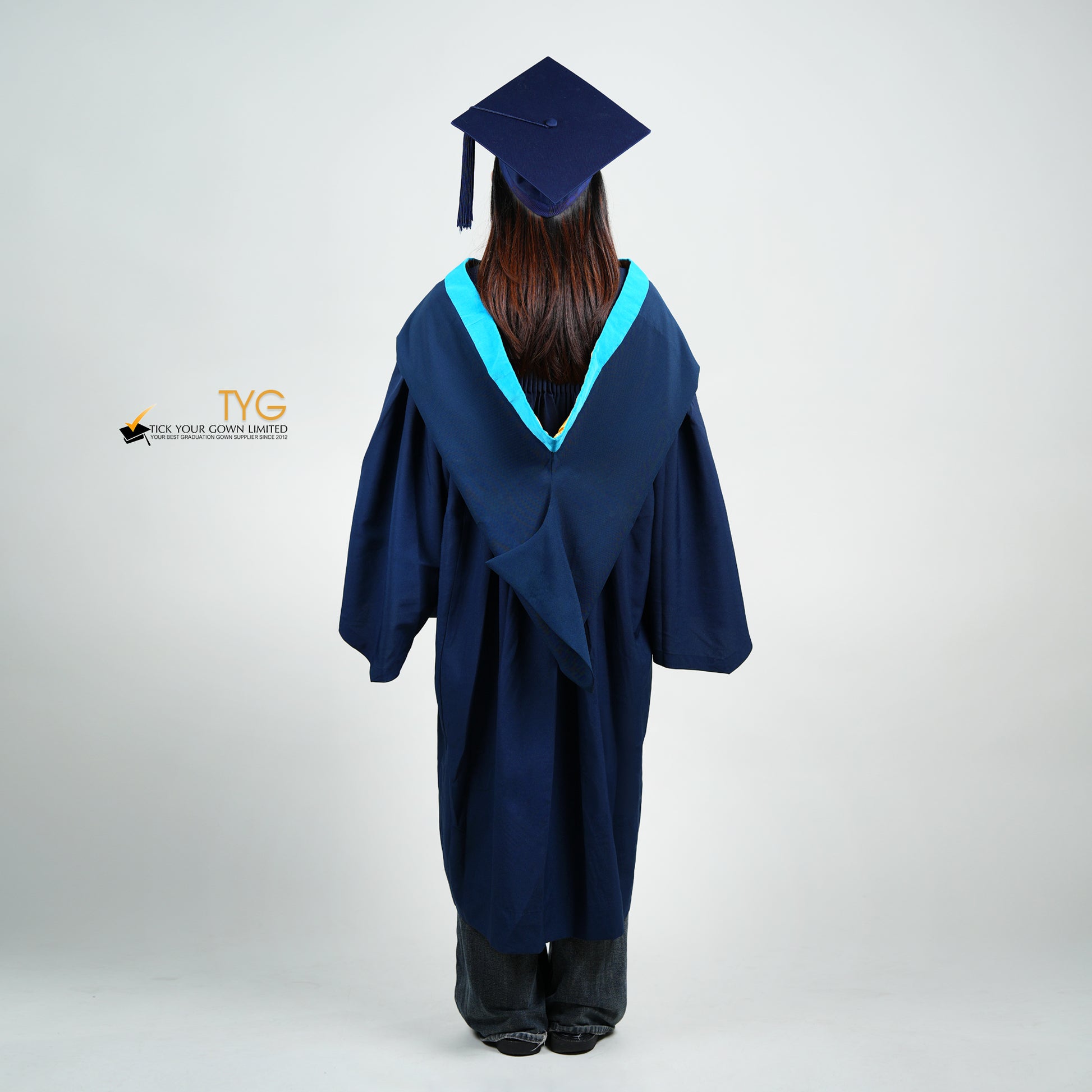A back view of a person wearing a navy blue graduation gown and cap on a white background with TYG logo.