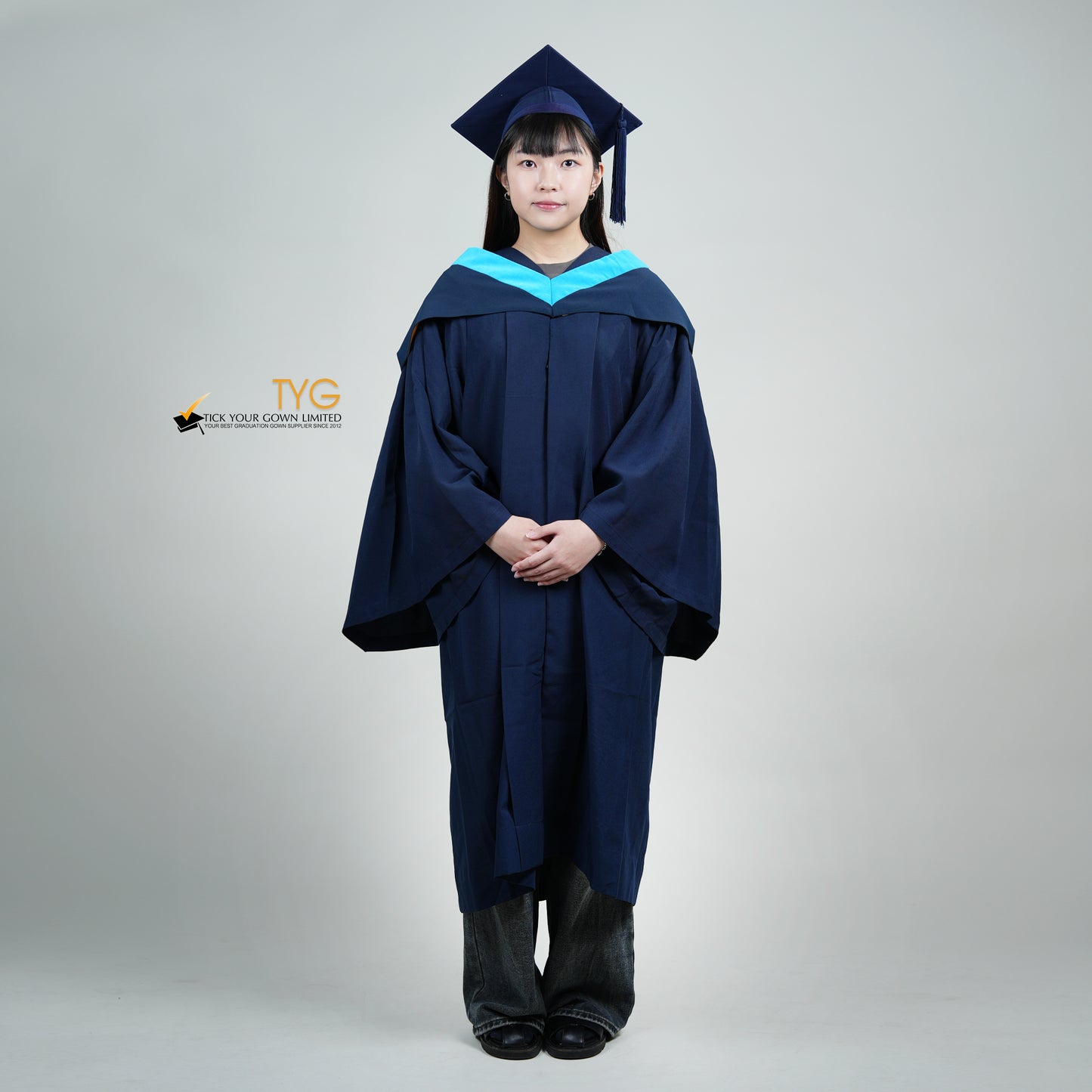 A person wearing a navy blue bachelor graduation gown with a light blue satin hood.