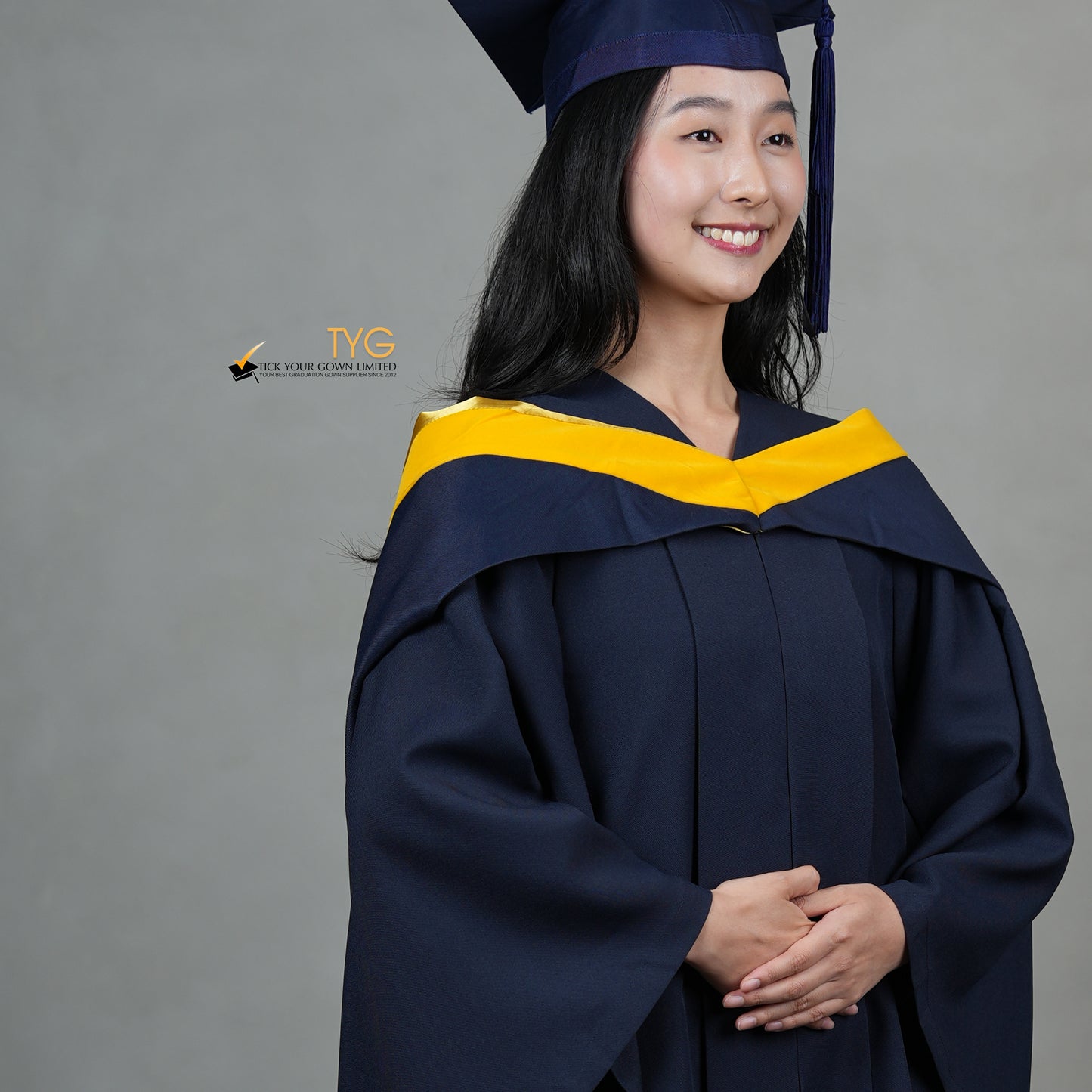 A detailed profile view of a graduate in a navy cap and gown with a yellow hood against a gray background
