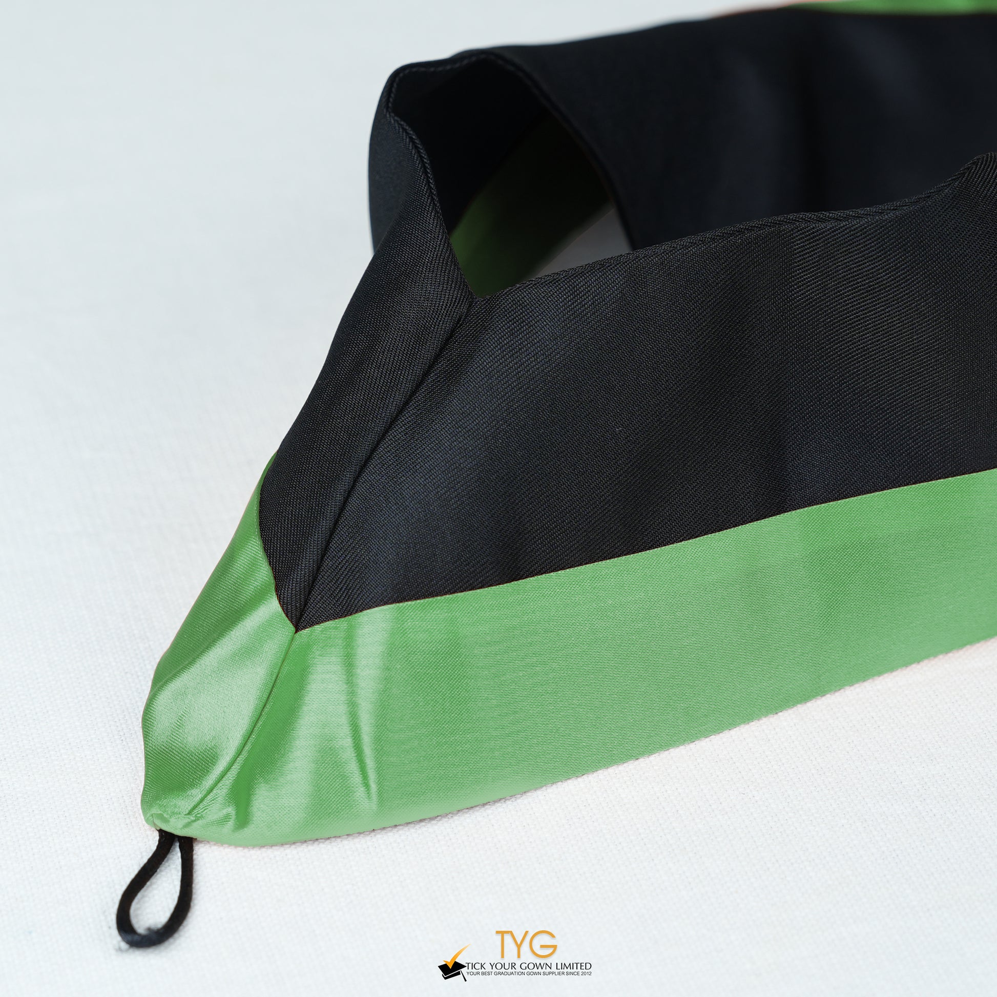 Detailed view of a bachelor’s graduation hood in black with green satin lining.