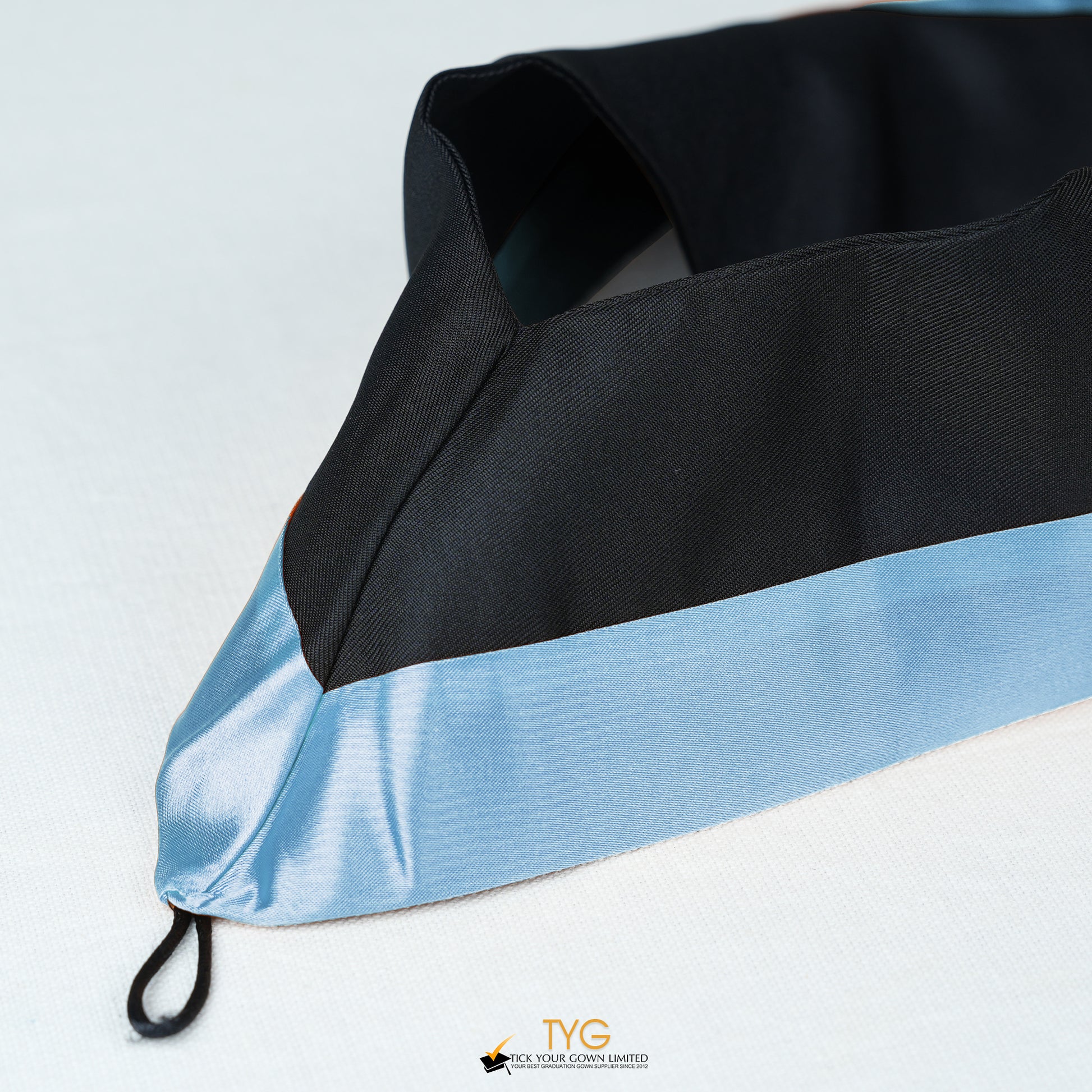 Detailed view of a bachelor’s graduation hood in black with light blue satin lining.