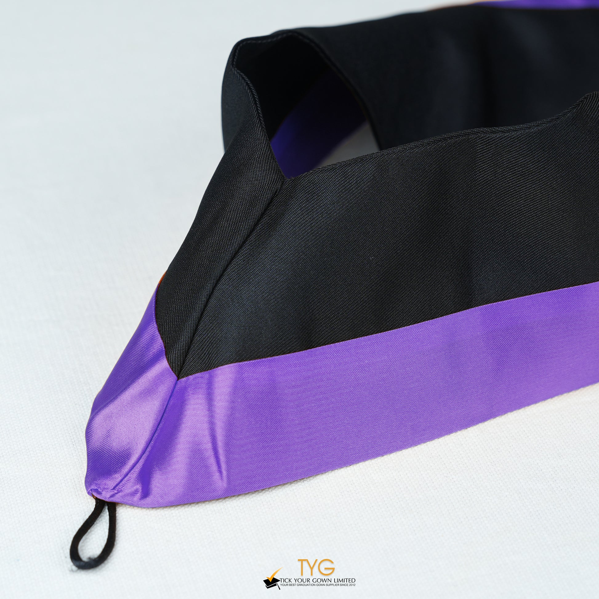 Detailed view of a bachelor’s graduation hood in black with purple satin lining.