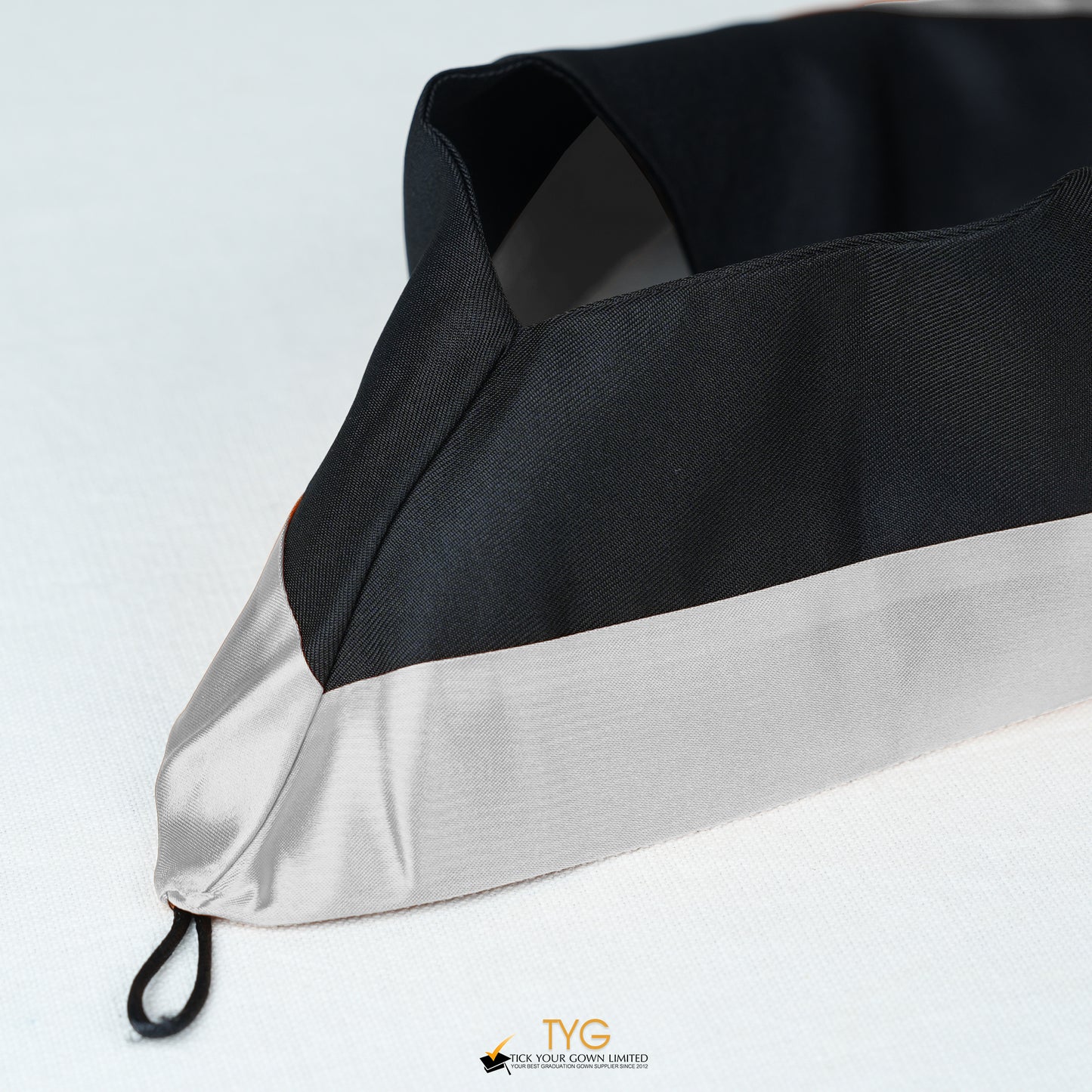 Detailed view of a bachelor’s graduation hood in black with silver satin lining.