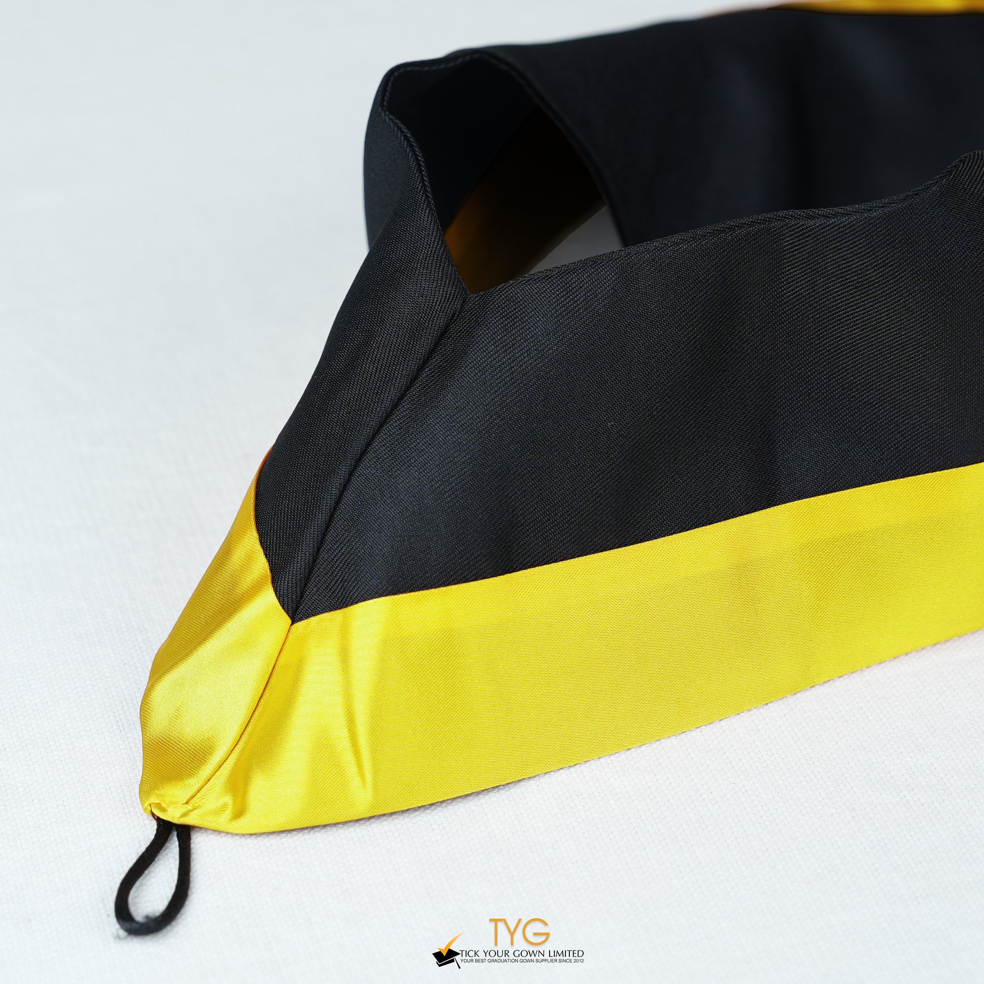 Detailed view of a bachelor’s graduation hood in black with yellow satin lining.