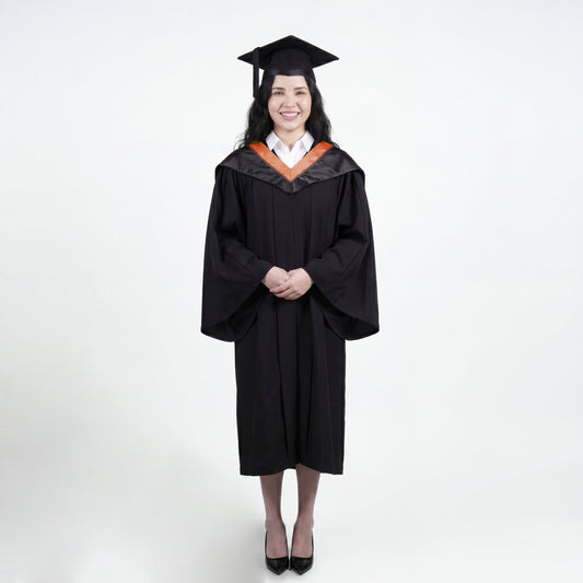 A woman wearing a black graduation gown and matching mortarboard cap stands against a light gray studio background.

The gown has a wide collar with copper and brown trim accent hood, and the model is posed with hands clasped in front.