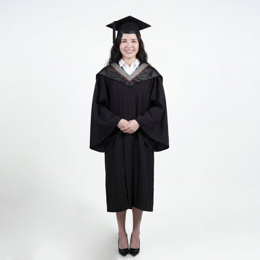 A woman wearing a black graduation gown and matching mortarboard cap stands against a light gray studio background.

The gown has a wide collar with grey and brown trim accent hood, and the model is posed with hands clasped in front.