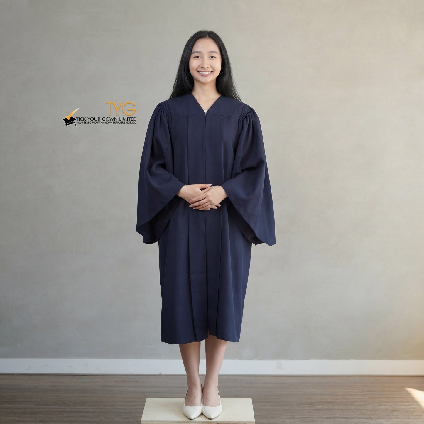 A person wearing a classic navy blue graduation gown against a plain background