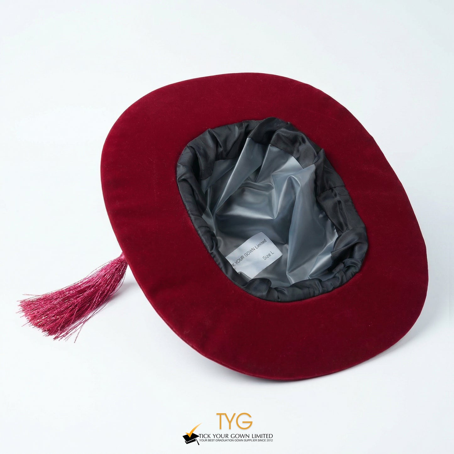 Inside view of a maroon velvet doctoral bonnet featuring a black inner band, silver lining, attached matching tassel, and a tag displaying "Size L" against a plain white background.