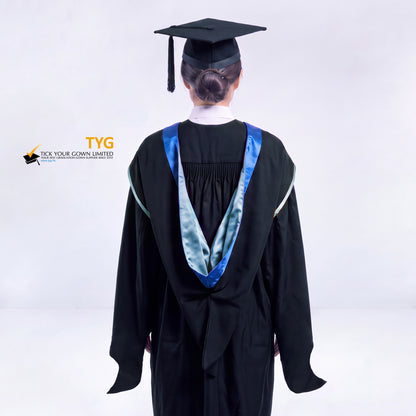 A back view of a woman in a black master's graduation gown classic UK with a blue hood with sky blue trim accent and with a black mortarboard cap with a black tassel against a gray background.
