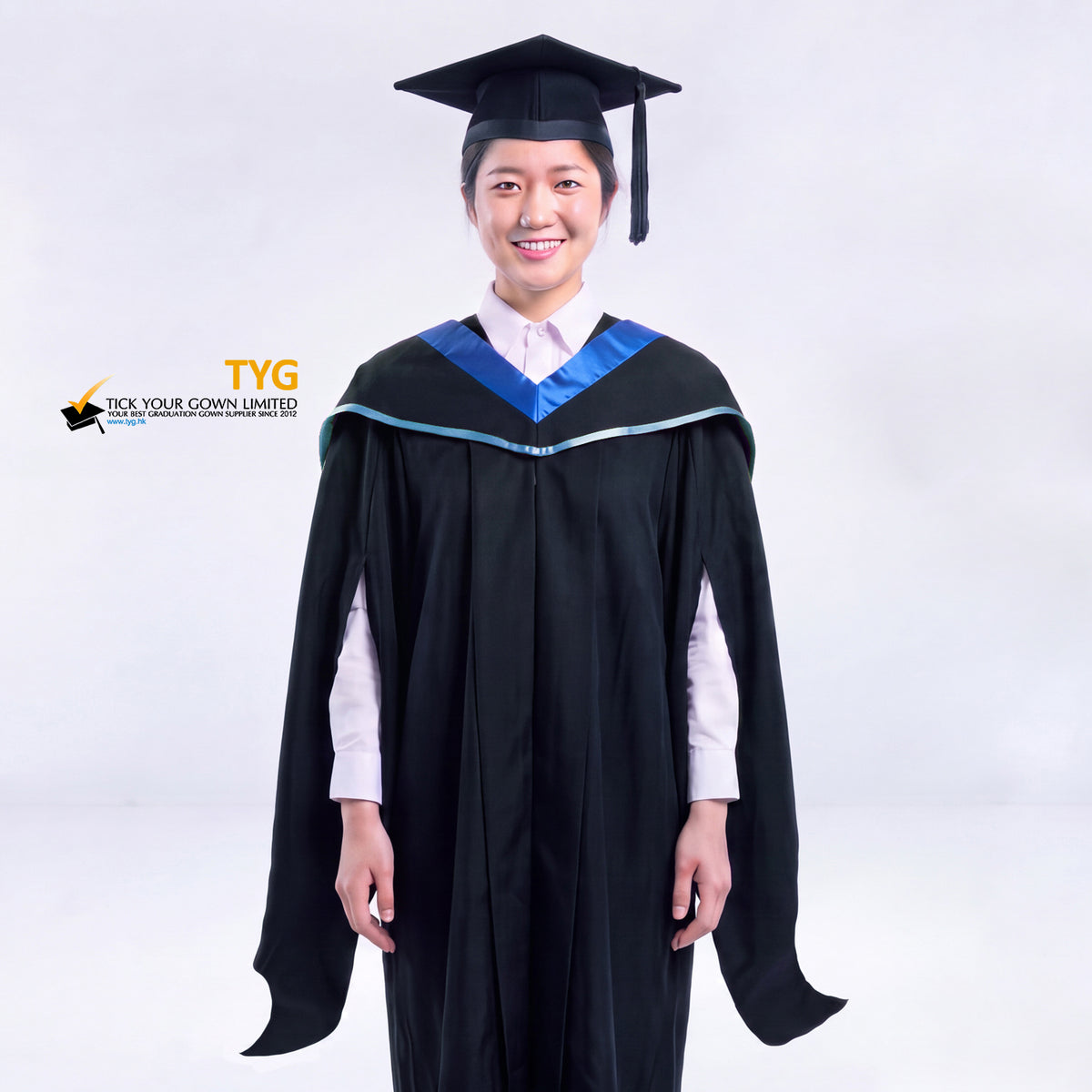 A woman in a black master's graduation gown classic UK with a blue hood with sky blue accent and with a black mortarboard cap with an black tassel against a gray background.