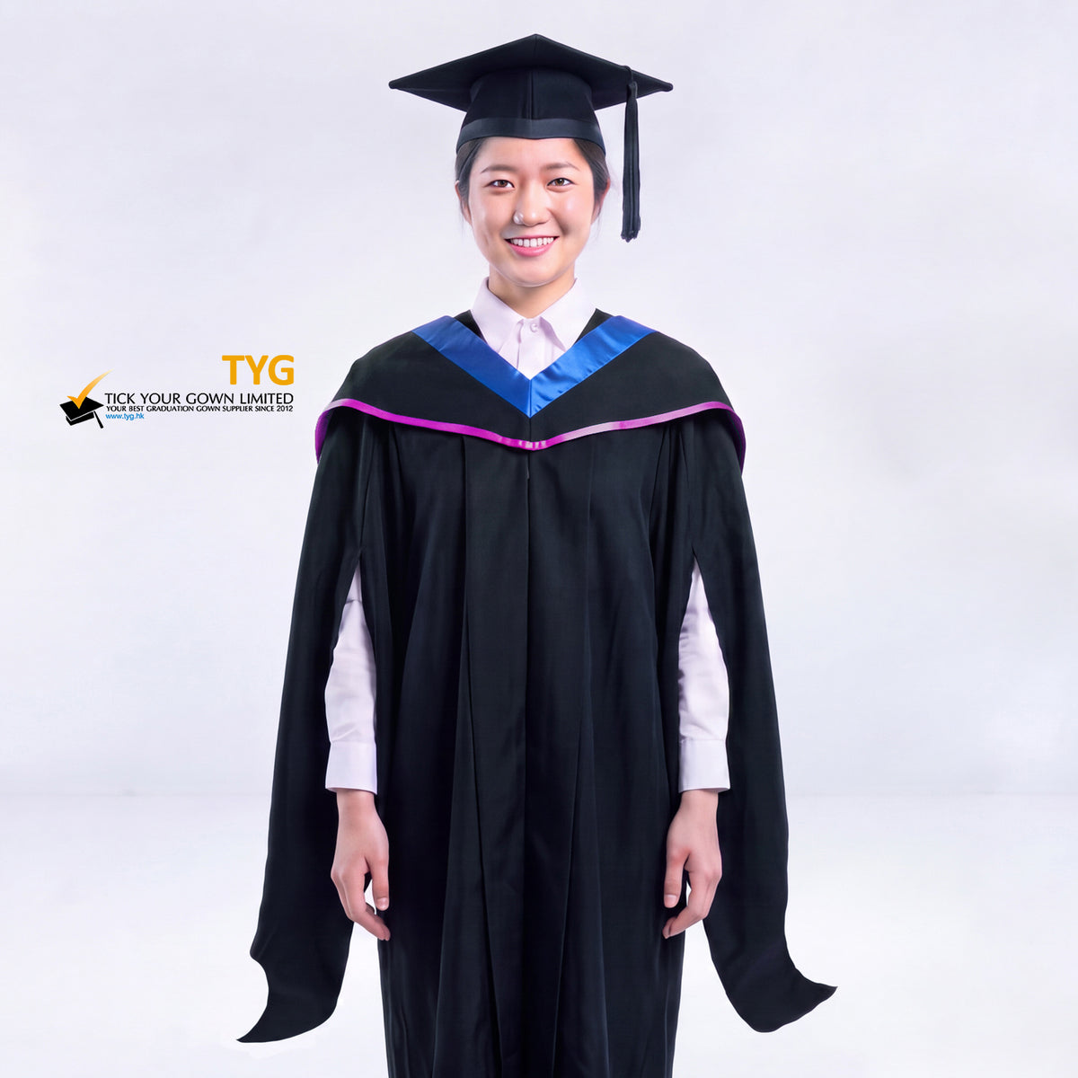 A woman in a black master's graduation gown classic UK with a blue hood with light purple accent and with a black mortarboard cap with an black tassel against a gray background.