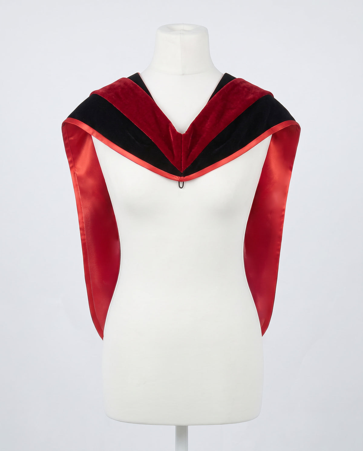 Master's graduation hood displayed on a mannequin showing full shape with black velvet body, red velvet hood and red satin lining.