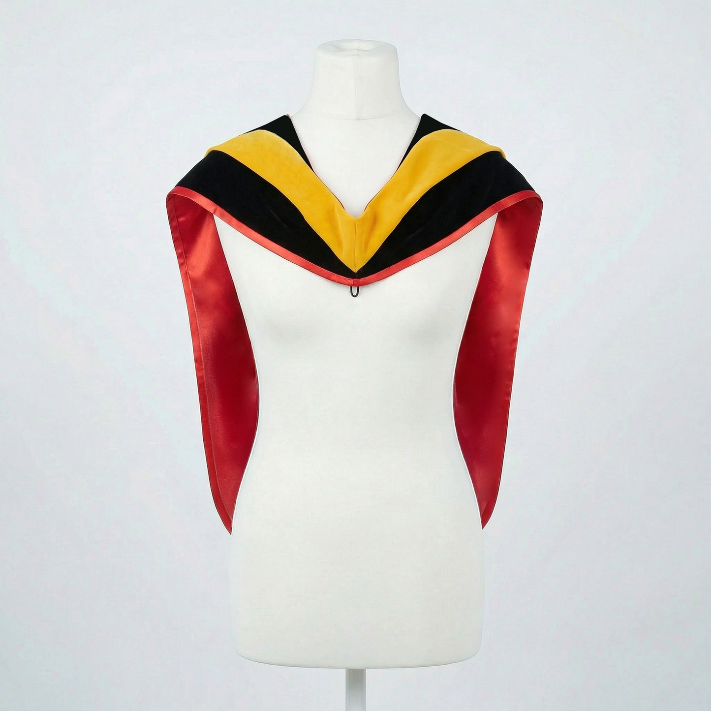Master's graduation hood displayed on a mannequin showing full shape with black velvet body, yellow velvet hood and red satin lining.
