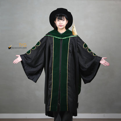 A showcase front view of a person wearing a PhD graduation gown in black with forest green velvet panels, matching sleeve bars, gold trim, and a matching doctoral bonnet with gold tassel.