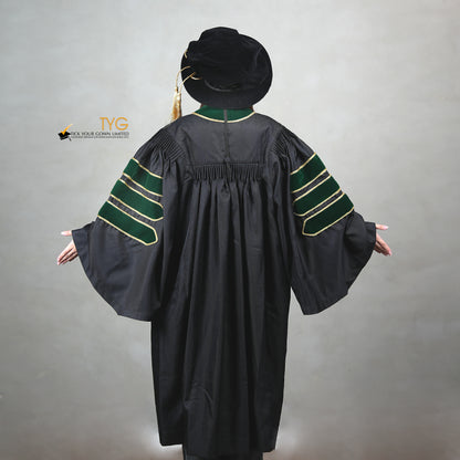 A back view of a person wearing a PhD graduation gown in black with forest green velvet panels, matching sleeve bars, gold trim, and a matching doctoral bonnet with gold tassel.