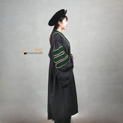 A side view of a person wearing a PhD graduation gown in black with forest green velvet panels, matching sleeve bars, gold trim, and a matching doctoral bonnet with gold tassel.