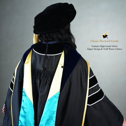 A back profile view of a person wearing a PhD classic black velvet graduation gown with silver sleeve bars, silver front trim, and a black doctoral bonnet with gold tassel.