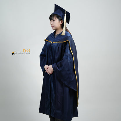 A profile view of a person wearing a PhD classic navy blue velvet graduation gown with yellow lining hood, and a navy blue doctoral bonnet with gold tassel.