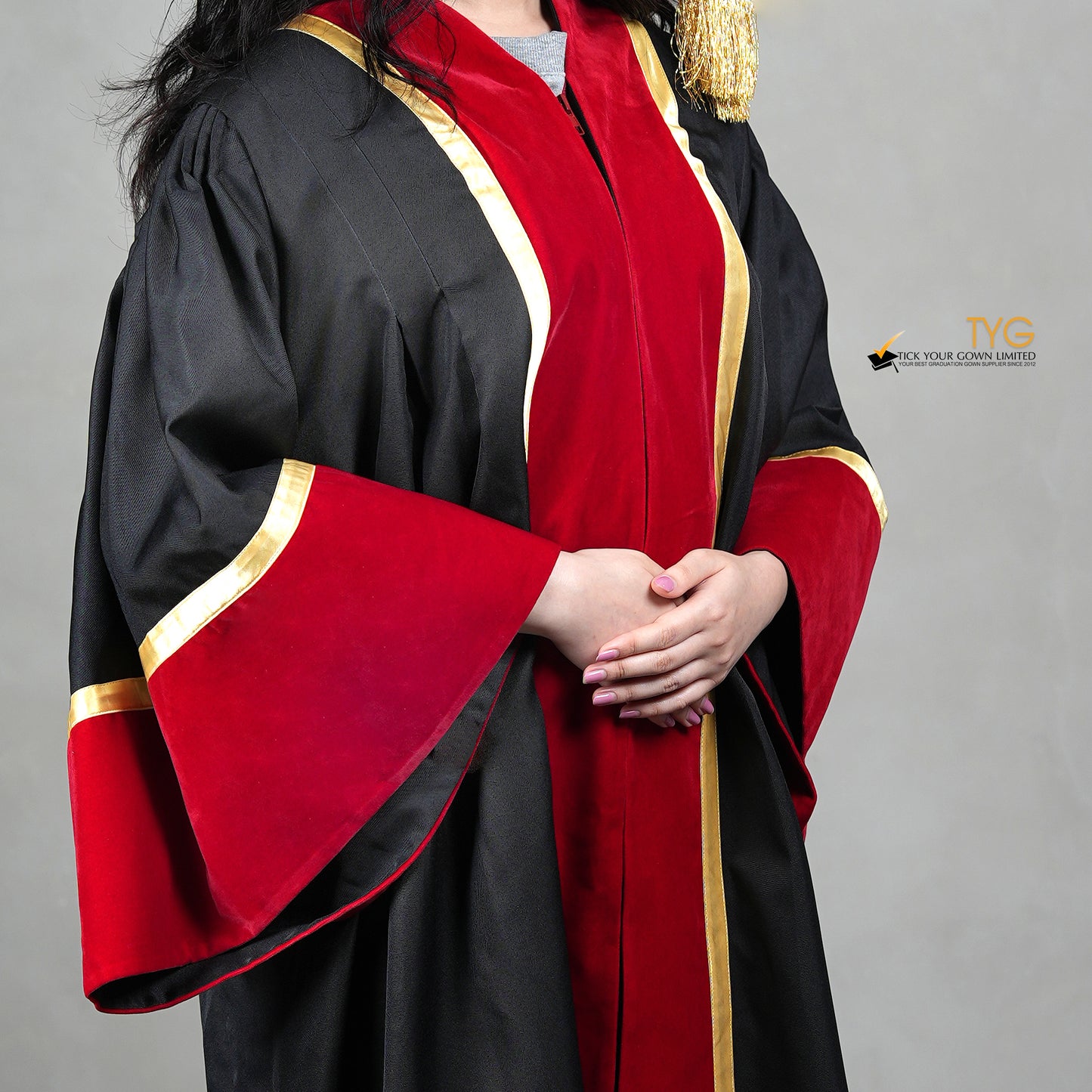 Detailed front view of an honorary gown in black with red velvet panels, gold trim, and red velvet sleeve cuffs