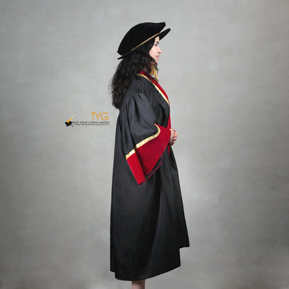 Profile view of a doctoral graduation gown in black with red velvet sleeve cuffs, gold trim, and a matching doctoral bonnet with gold tassel