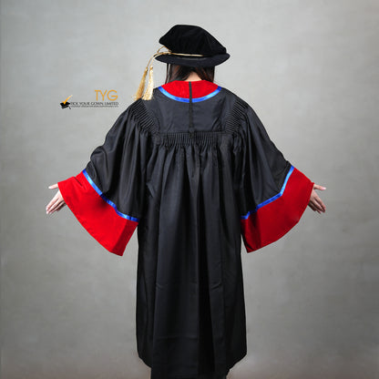 A back view of a person wearing a premium honorary graduation gown in black with red velvet panels, royal blue trim, red velvet sleeve cuffs, and a matching doctoral bonnet with gold tassel.