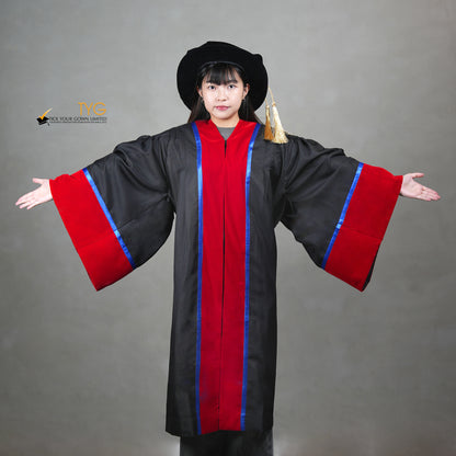 A front view of a person wearing and showcasing a premium honorary graduation gown in black with red velvet panels, royal blue trim, red velvet sleeve cuffs, and a matching doctoral bonnet with gold tassel.