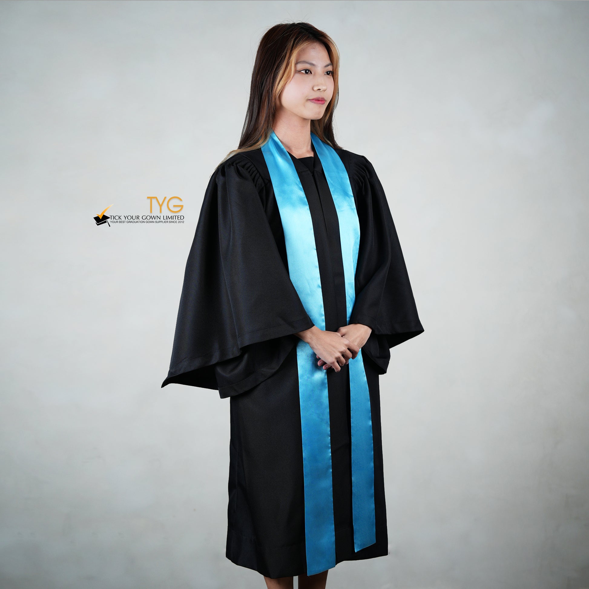 Profile view of a person wearing a black graduation gown with a sky blue stole on a gray background