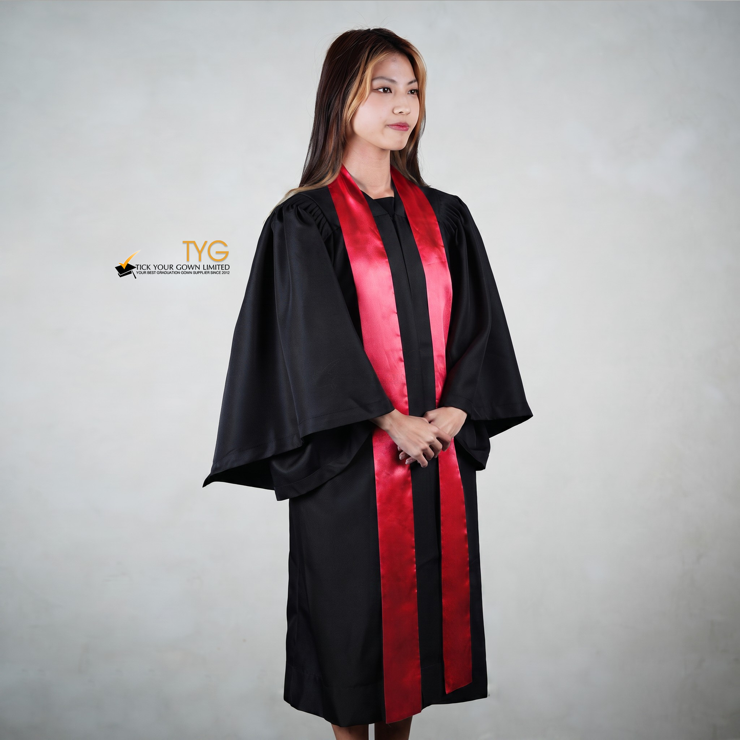 Profile view of a person wearing a black graduation gown with a red stole on a gray background
